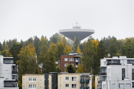 View of the Jyvaskyla water tower rising above a forest with autumn colored trees and modern residential buildings in the foreground in Jyvaskyla Central Finland Finland.