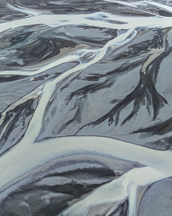 Aerial view of a complex braided river system with glacial water flowing through dark volcanic sand deposits in Iceland. Aerial view of a complex braided river system with glacial water flowing through dark volcanic sand deposits in Iceland.