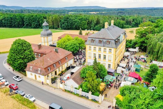 Aerial view of Schloss Jagersburg with a crowd of people at an outdoor event surrounded by lush green trees and agricultural fields in Eggolsheim Bayern Germany. Aerial view of Schloss Jagersburg with a crowd of people at an outdoor event surrounded by lush green trees and agricultural fields in Eggolsheim Bayern Germany.
