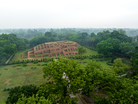 Aerial view of the ancient Gokul Medh archaeological site with its terraced brick structure surrounded by lush green trees and gardens in Bogura Rajshahi Division Bangladesh.