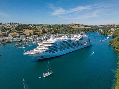 Fowey United Kingdom 10 August 2026 Aerial view of a large cruise ship in the Fowey river surrounded by small boats and the historic town of Fowey with hillside buildings under a blue sky. Fowey United Kingdom 10 August 2026 Aerial view of a large cruise ship in the Fowey river surrounded by small boats and the historic town of Fowey with hillside buildings under a blue sky.