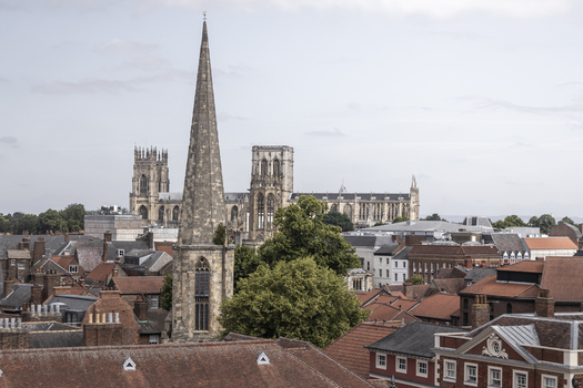 Aerial view of York Minster rising above the historic red tiled rooftops and stone buildings of the city center in York England United Kingdom.