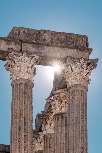 Evora Portugal 09 September 2026 View of the Roman Temple of Evora featuring ornate Corinthian columns against a clear blue sky with sunlight streaming through the stone structure. Evora Portugal 09 September 2026 View of the Roman Temple of Evora featuring ornate Corinthian columns against a clear blue sky with sunlight streaming through the stone structure.