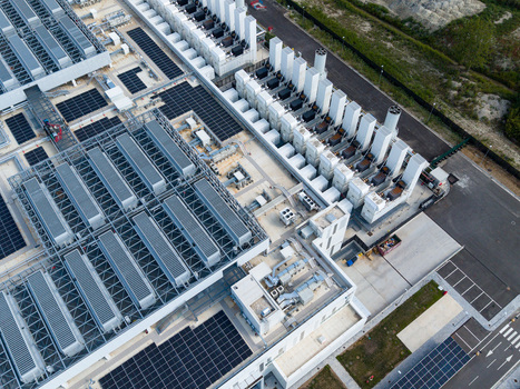 Aerial view of a modern data center campus with industrial cooling units solar panels and advanced digital infrastructure in Melegnano Lombardy Italy.