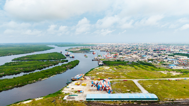 Aerial view of the industrial port area in Satellite Town with shipping containers warehouses and a river winding through the landscape in Lagos Lagos Nigeria.