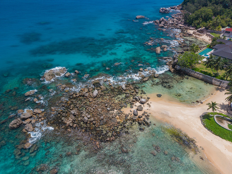 Aerial view of the rocky shoreline meeting the turquoise sea with sandy beaches nestled amidst the boulders Vista do Mar Mahe island Seychelles. Aerial view of the rocky shoreline meeting the turquoise sea with sandy beaches nestled amidst the boulders Vista do Mar Mahe island Seychelles.
