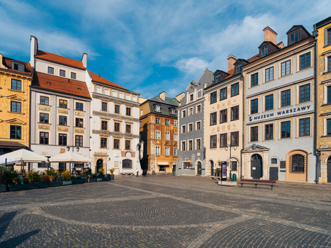View of Warsaw Old Town square featuring historic colorful buildings with ornate facades cobblestone pavement and a clear blue sky in Warsaw Masovian Voivodeship Poland. View of Warsaw Old Town square featuring historic colorful buildings with ornate facades cobblestone pavement and a clear blue sky in Warsaw Masovian Voivodeship Poland.