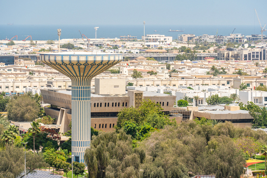 Aerial view of the blue and white striped water tower surrounded by lush green trees and low rise urban architecture with the sea in the background in Dubai Dubai United Arab Emirates. Aerial view of the blue and white striped water tower surrounded by lush green trees and low rise urban architecture with the sea in the background in Dubai Dubai United Arab Emirates.