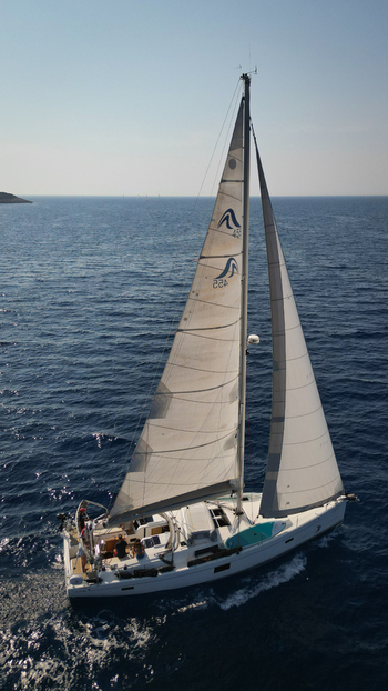 Hvar Croatia 22 August 2023 Aerial view of a white sailboat with people on deck cruising through the deep blue Adriatic sea under a clear sky. Hvar Croatia 22 August 2023 Aerial view of a white sailboat with people on deck cruising through the deep blue Adriatic sea under a clear sky.