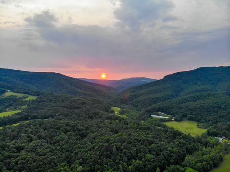 Lost City United States 12 June 2019 Aerial view of a sunset over the lush green forested hills and valleys with a soft pink and orange sky at dusk. Lost City United States 12 June 2019 Aerial view of a sunset over the lush green forested hills and valleys with a soft pink and orange sky at dusk.