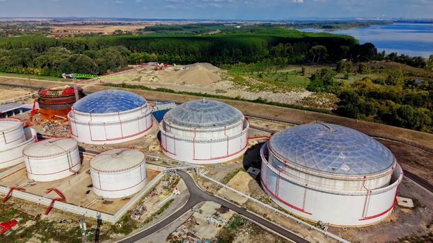 Aerial view of industrial fuel storage tanks with dome roofs situated in a rural landscape near a river showing construction activity and surrounding greenery in Kovin Vojvodina Serbia. Aerial view of industrial fuel storage tanks with dome roofs situated in a rural landscape near a river showing construction activity and surrounding greenery in Kovin Vojvodina Serbia.