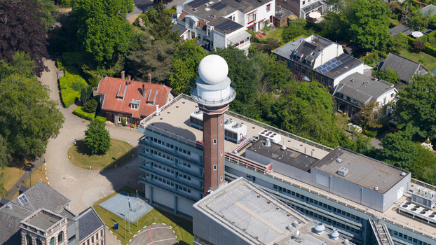 Aerial view of the KNMI building featuring its iconic radar tower and white dome surrounded by lush green trees and residential houses in De Bilt Utrecht Netherlands. Aerial view of the KNMI building featuring its iconic radar tower and white dome surrounded by lush green trees and residential houses in De Bilt Utrecht Netherlands.
