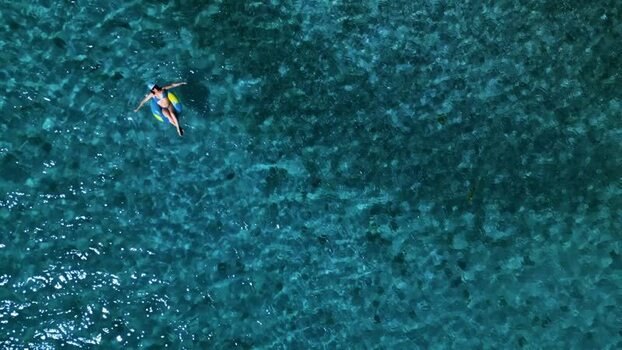Aerial view of a woman floating on an inflatable ring in the sea Honduras. Aerial view of a woman floating on an inflatable ring in the sea Honduras.