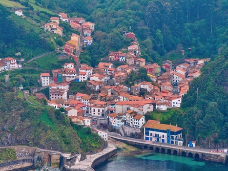 Aerial view of the colorful houses of Cudillero village nestled in a steep green valley overlooking the harbor in Cudillero Asturias Spain. Aerial view of the colorful houses of Cudillero village nestled in a steep green valley overlooking the harbor in Cudillero Asturias Spain.