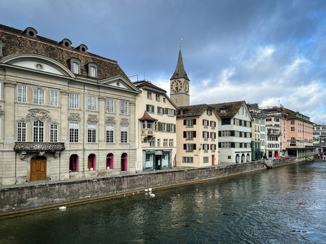 View of St. Peter Church with its iconic clock tower overlooking the Limmat River surrounded by historic architecture in Zurich Zurich Switzerland.