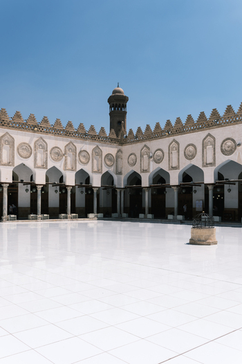 View of the white marble courtyard and arched colonnade of the Al Azhar Mosque under a clear blue sky in Cairo Egypt. View of the white marble courtyard and arched colonnade of the Al Azhar Mosque under a clear blue sky in Cairo Egypt.