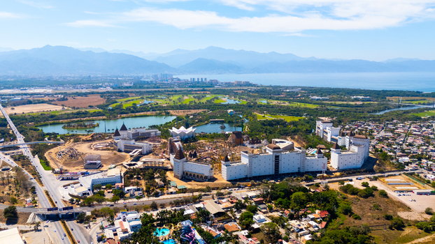 Aerial view of a sprawling resort complex nestled amid lush greenery and distant mountains under a clear sky Nuevo Vallarta Mexico.