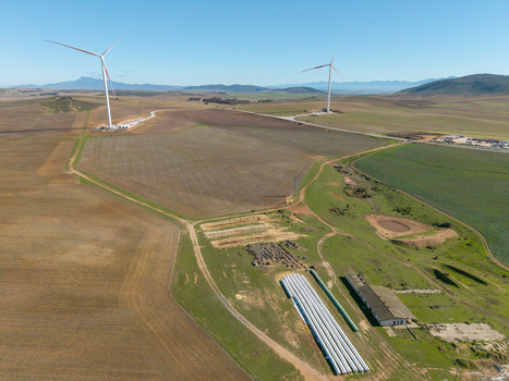 Aerial view of wind turbines standing in vast agricultural fields under a clear blue sky with distant mountains Swellendam Western Cape South Africa. Aerial view of wind turbines standing in vast agricultural fields under a clear blue sky with distant mountains Swellendam Western Cape South Africa.