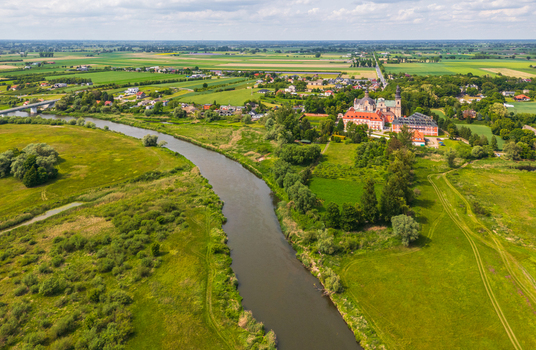 Aerial view of the Cistercian Abbey in the Nadwarcianski Park Krajobrazowy with the Warta River winding through green meadows and fields in Lad Greater Poland Voivod Poland. Aerial view of the Cistercian Abbey in the Nadwarcianski Park Krajobrazowy with the Warta River winding through green meadows and fields in Lad Greater Poland Voivod Poland.