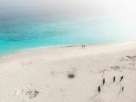Aerial view of a pristine white beach contrasting with brilliant turquoise waters with people enjoying the shore Hoarafushi Thiladhunmathee Uthuruburi Maldives. Aerial view of a pristine white beach contrasting with brilliant turquoise waters with people enjoying the shore Hoarafushi Thiladhunmathee Uthuruburi Maldives.