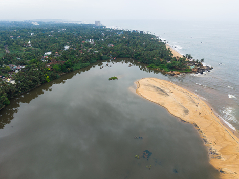 Aerial view of a coastal lagoon meeting the Indian Ocean with sandy beaches and lush tropical palm trees in Galle Southern Province Sri Lanka. Aerial view of a coastal lagoon meeting the Indian Ocean with sandy beaches and lush tropical palm trees in Galle Southern Province Sri Lanka.