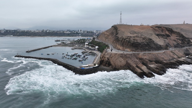 Aerial view of the coastal harbor in Barranco with small fishing boats docked in the bay rocky cliffs and the Pacific Ocean under a cloudy sky in Barranco Lima Province Peru.