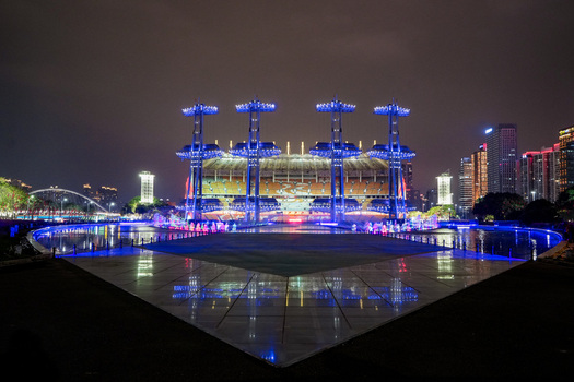 Guangzhou Guangdong Province China 24 February 2024 View of Haixinsha Asian Games Park stadium illuminated with blue lights at night with a reflective water pool in the foreground. Guangzhou Guangdong Province China 24 February 2024 View of Haixinsha Asian Games Park stadium illuminated with blue lights at night with a reflective water pool in the foreground.