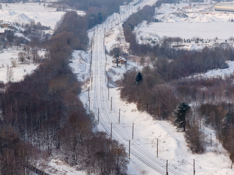 Aerial view of snow covered railway tracks passing through a dense winter forest with bare trees and power lines Lithuania. Aerial view of snow covered railway tracks passing through a dense winter forest with bare trees and power lines Lithuania.