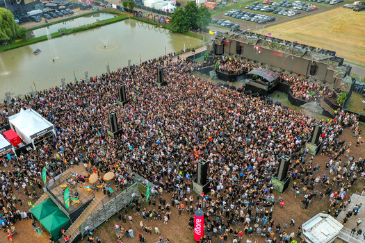 Herzogenaurach Germany 24 July 2025 Aerial view of the Open Beatz Festival with a large crowd gathered in front of the main stage next to a pond with fountains.