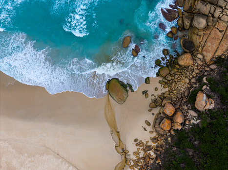 Aerial view of Bettys Beach with turquoise ocean waves crashing against sandy shores and large granite boulders along the coastline in Albany WA Australia. Aerial view of Bettys Beach with turquoise ocean waves crashing against sandy shores and large granite boulders along the coastline in Albany WA Australia.