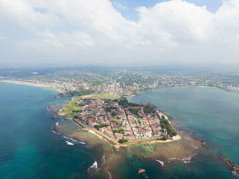 Aerial view of Galle Fort on a peninsula surrounded by turquoise ocean water and the city skyline under a cloudy sky Galle Southern Province Sri Lanka. Aerial view of Galle Fort on a peninsula surrounded by turquoise ocean water and the city skyline under a cloudy sky Galle Southern Province Sri Lanka.
