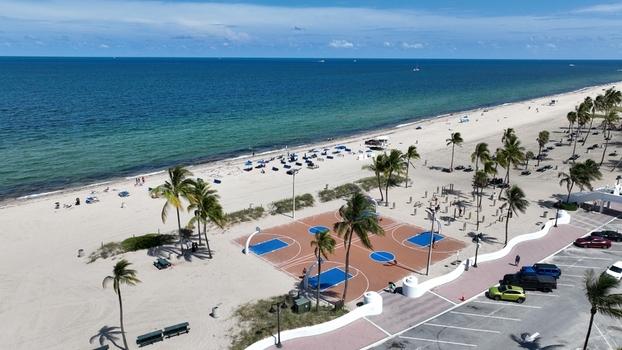 Aerial view of a basketball court on the sand next to the beach with turquoise waters and palm trees Fort Lauderdale USA.