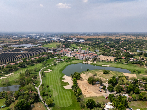 Ahmedabad India 21 March 2026 Aerial view of Kalhaar Blues and Greens Golf Club featuring lush green fairways a central lake and surrounding landscape.