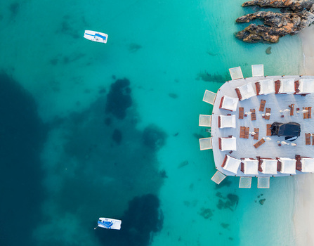 Aerial view of a luxury beach club pier with white cabanas and sunbeds over turquoise crystal clear water Ksamil Vlore County Albania. Aerial view of a luxury beach club pier with white cabanas and sunbeds over turquoise crystal clear water Ksamil Vlore County Albania.