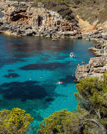 Mallorca Spain 15 September 2023 View of the turquoise waters of a cove in Mallorca with people swimming and relaxing on the rocky cliffs. Mallorca Spain 15 September 2023 View of the turquoise waters of a cove in Mallorca with people swimming and relaxing on the rocky cliffs.
