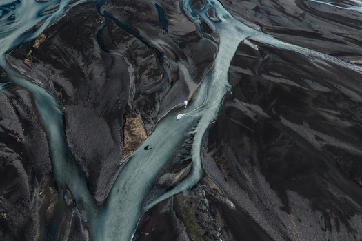 Aerial view of a braided river flowing through dark volcanic sand in Skaftarhreppur Iceland.