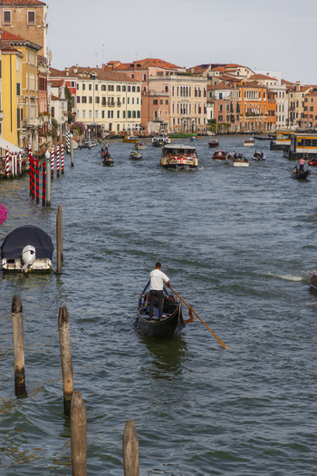 Venice Italy 21 September 2026 View of a gondolier rowing a traditional gondola on the Grand Canal with historic buildings water taxis and wooden mooring poles. Venice Italy 21 September 2026 View of a gondolier rowing a traditional gondola on the Grand Canal with historic buildings water taxis and wooden mooring poles.