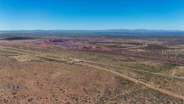 Aerial view of a vast arid landscape scarred by a sprawling industrial complex with a long road and railway line cutting through Rustenburg North West South Africa. Aerial view of a vast arid landscape scarred by a sprawling industrial complex with a long road and railway line cutting through Rustenburg North West South Africa.