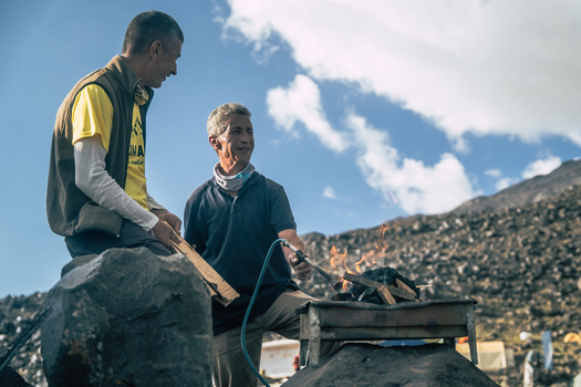 Turkey 14 August 2023 View of two men preparing a fire on a small grill on the rocky slopes of Mount Ararat in Turkey with a blue sky and clouds in the background. Turkey 14 August 2023 View of two men preparing a fire on a small grill on the rocky slopes of Mount Ararat in Turkey with a blue sky and clouds in the background.