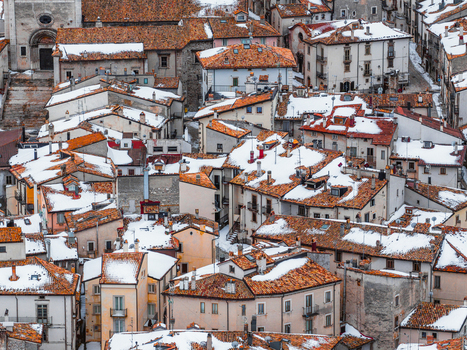 Aerial view of the historic town featuring snow covered terracotta rooftops and traditional stone buildings in Pescocostanzo Abruzzo Italy.