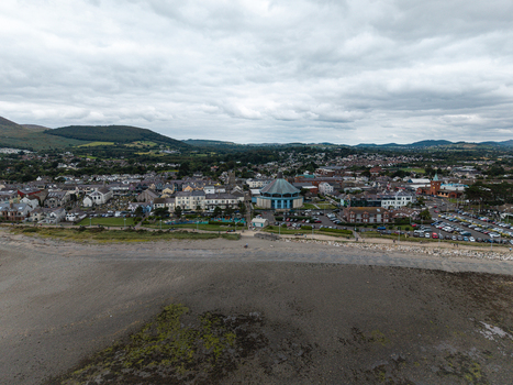 Aerial view of the coastal town featuring its sandy beach urban buildings and the Mourne Mountains in the background in Newcastle Northern Ireland United Kingdom. Aerial view of the coastal town featuring its sandy beach urban buildings and the Mourne Mountains in the background in Newcastle Northern Ireland United Kingdom.