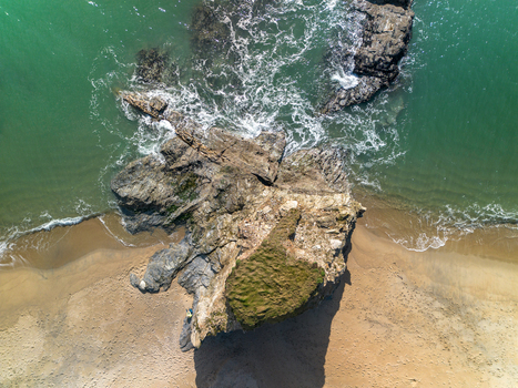 Aerial view of a large rock formation on the sandy beach at Carlyon Bay with turquoise waves crashing against the shore Carlyon Bay Cornwall United Kingdom. Aerial view of a large rock formation on the sandy beach at Carlyon Bay with turquoise waves crashing against the shore Carlyon Bay Cornwall United Kingdom.