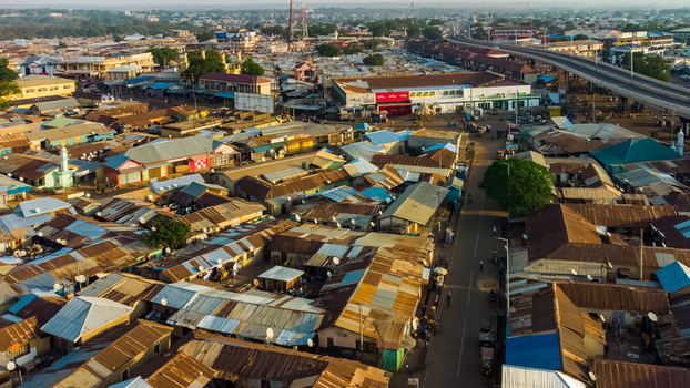 Aerial view of the dense urban landscape of Tamale featuring corrugated metal rooftops a major road and an overpass under warm light in Tamale Northern Region Ghana. Aerial view of the dense urban landscape of Tamale featuring corrugated metal rooftops a major road and an overpass under warm light in Tamale Northern Region Ghana.