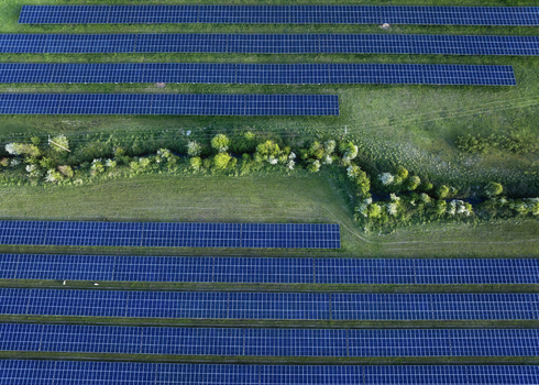 Aerial view of Gillinstown Solar Farm with rows of blue solar panels on green fields in County Meath Ireland.