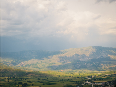 Aerial view of the lush green valley and rugged mountain ranges under a dramatic cloudy sky in Gjirokaster Gjirokaster County Albania. Aerial view of the lush green valley and rugged mountain ranges under a dramatic cloudy sky in Gjirokaster Gjirokaster County Albania.
