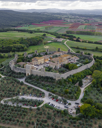Aerial view of the historic walled town of Monteriggioni with medieval fortifications stone buildings and olive groves in the Tuscan countryside Monteriggioni Tuscany Italy.
