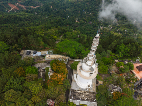 Aerial view of Ambuluwawa Tower with its unique spiral architecture and people on the stairs surrounded by lush green forests and mist in Gampola Central Province Sri Lanka. Aerial view of Ambuluwawa Tower with its unique spiral architecture and people on the stairs surrounded by lush green forests and mist in Gampola Central Province Sri Lanka.