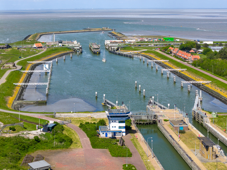 Aerial view of the Lorentzsluizen lock complex featuring water gates control buildings and maritime infrastructure under a clear sky in Kornwerderzand Friesland Netherlands.