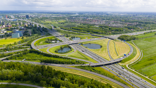 Aerial view of the Knooppunt Oudenrijn highway interchange with green fields and circular loops under a bright sky in Utrecht Utrecht Netherlands. Aerial view of the Knooppunt Oudenrijn highway interchange with green fields and circular loops under a bright sky in Utrecht Utrecht Netherlands.