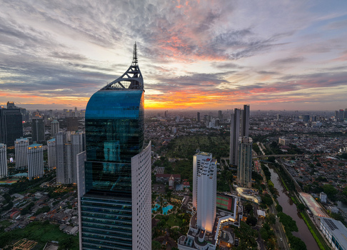 Aerial view of the Wisma 46 skyscraper along Jalan Jendral Sudirman surrounded by the urban skyline during a vibrant sunset in Kecamatan Setiabudi Daerah Khusus Ibukota Indonesia. Aerial view of the Wisma 46 skyscraper along Jalan Jendral Sudirman surrounded by the urban skyline during a vibrant sunset in Kecamatan Setiabudi Daerah Khusus Ibukota Indonesia.
